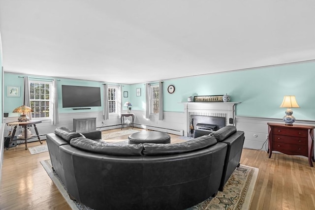 living room with a brick fireplace, light hardwood / wood-style flooring, and a baseboard radiator