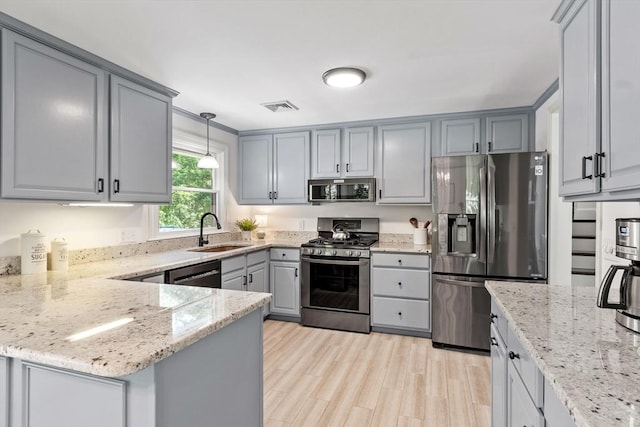 18 Mann St, Bellingham, MA 02019 - kitchen with appliances with stainless steel finishes, gray cabinetry, a peninsula, light stone countertops, and decorative light fixtures