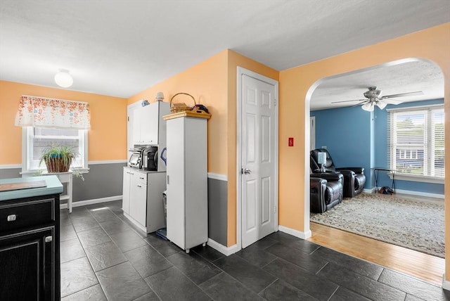 kitchen featuring arched walkways, a ceiling fan, and baseboards