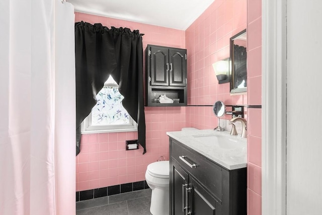 bathroom with tile walls, tile patterned flooring, toilet, and vanity