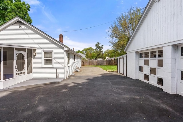 view of property exterior featuring a chimney, fence, and a garage