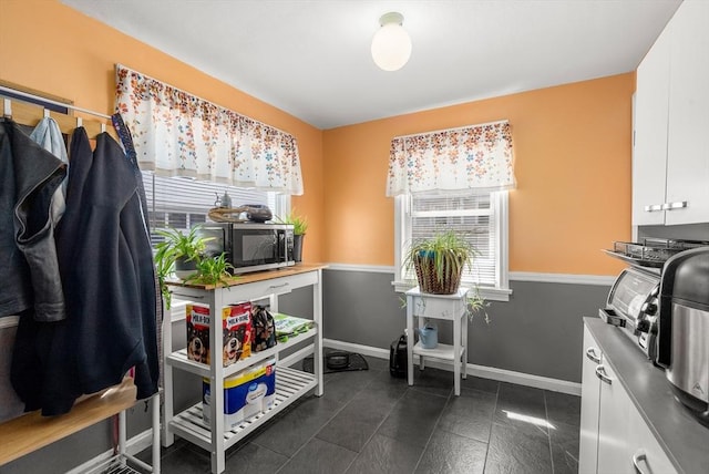 interior space with stainless steel microwave, plenty of natural light, and white cabinetry