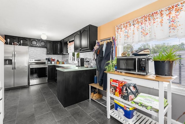 kitchen with stainless steel appliances, a sink, light countertops, and dark cabinetry