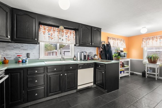 kitchen featuring white dishwasher, a sink, dark cabinetry, and light countertops