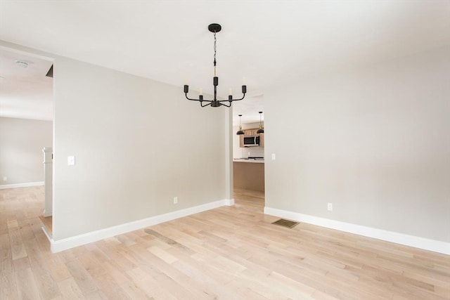 unfurnished dining area featuring a chandelier, light wood-type flooring, visible vents, and baseboards