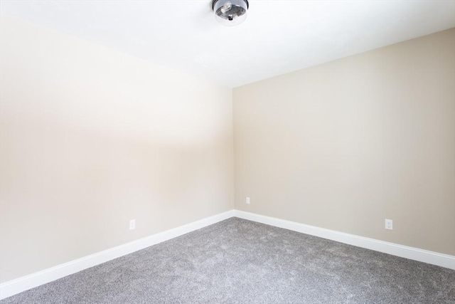 carpeted empty room featuring baseboards