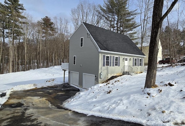 view of front of home featuring a garage, roof with shingles, and driveway