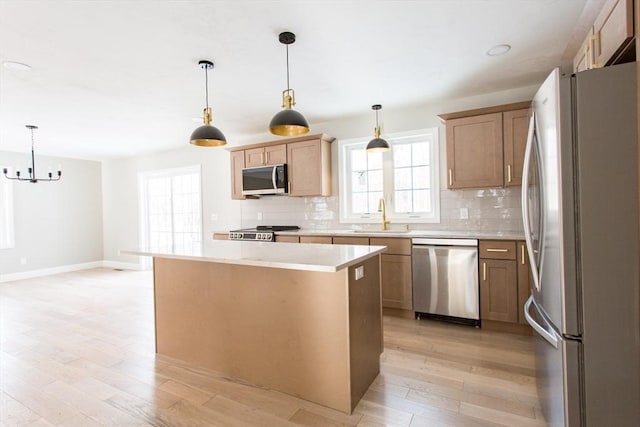 kitchen with light wood-style floors, appliances with stainless steel finishes, light countertops, and a sink