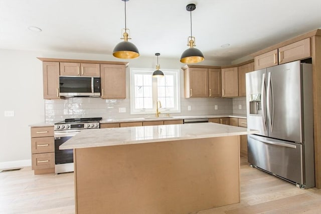 kitchen with light wood-style flooring, a sink, appliances with stainless steel finishes, backsplash, and a center island