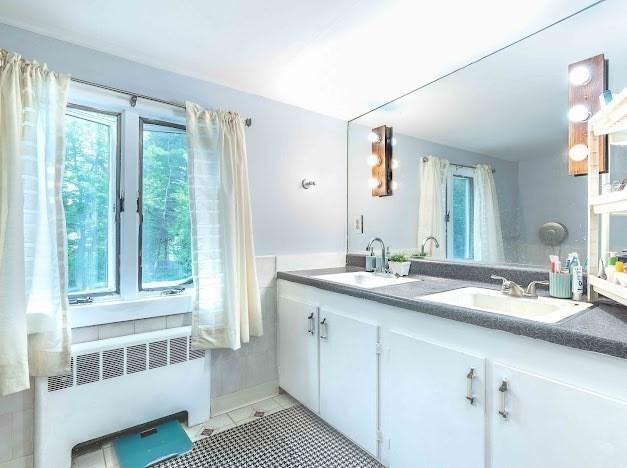 26 Beulah St, Framingham, MA 01701 - full bath with radiator, double vanity, healthy amount of natural light, and tile patterned floors