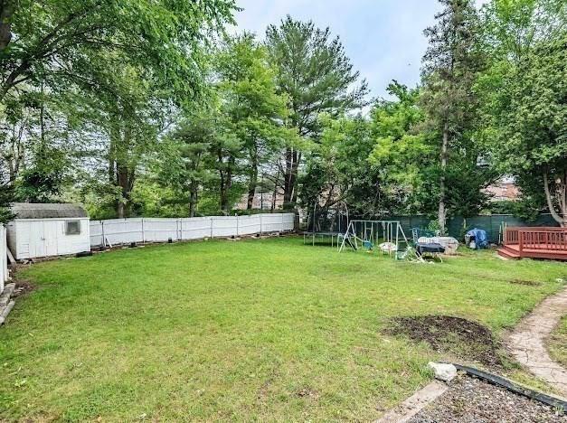 26 Beulah St, Framingham, MA 01701 - fenced backyard with a trampoline, a shed, a playground, and a wooden deck