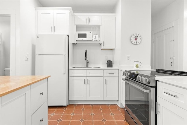 kitchen featuring butcher block countertops, a sink, white cabinetry, and white appliances