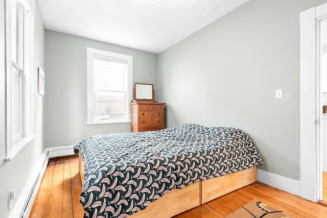 bedroom with wood-type flooring, a baseboard radiator, and baseboards