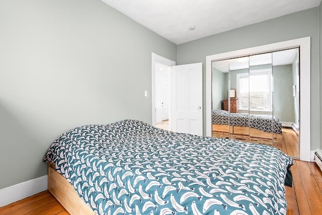 bedroom with baseboards, wood-type flooring, and a closet