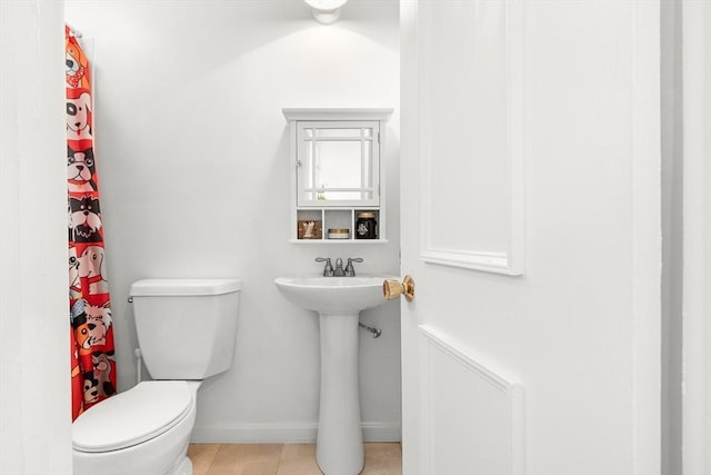bathroom with baseboards, tile patterned flooring, and toilet