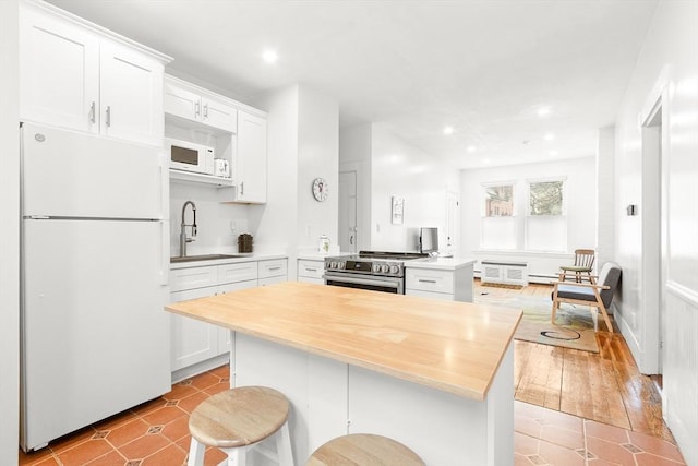 kitchen featuring recessed lighting, a sink, white cabinets, and white appliances