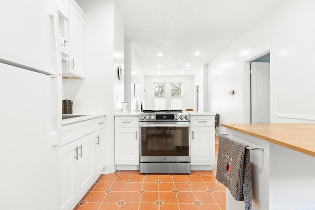 kitchen with stainless steel electric range, light countertops, white cabinets, freestanding refrigerator, and a peninsula