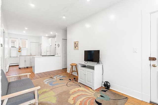 living area featuring recessed lighting, baseboards, a baseboard heating unit, and light wood-type flooring