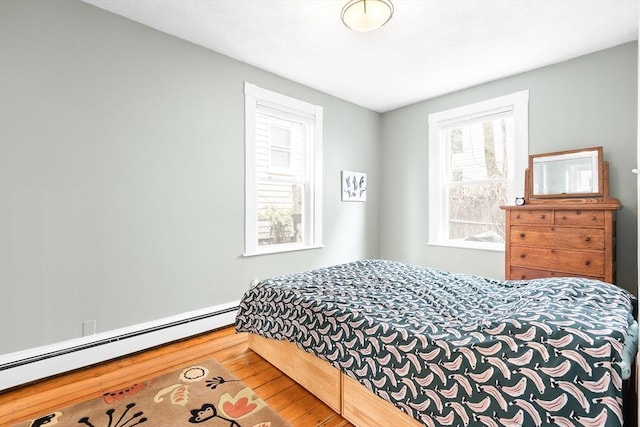 bedroom featuring a baseboard heating unit and wood finished floors