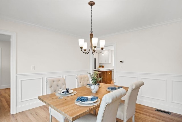 7 Locust St, Woburn, MA 01801 - dining room with a chandelier, ornamental molding, a decorative wall, a wainscoted wall, and light wood finished floors