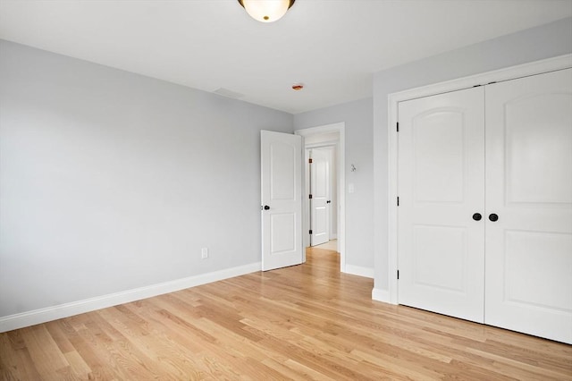 7 Locust St, Woburn, MA 01801 - unfurnished bedroom featuring baseboards, light wood-style floors, and a closet