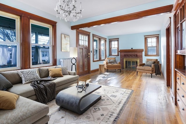 living room featuring a fireplace, light hardwood / wood-style floors, and an inviting chandelier