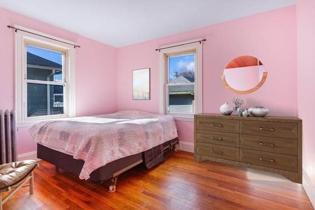 bedroom with radiator heating unit and dark wood-type flooring