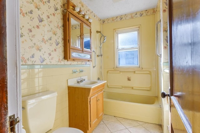 full bathroom with washtub / shower combination, tile patterned floors, toilet, vanity, and tile walls