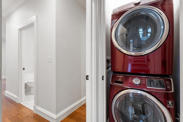 laundry room featuring stacked washer / drying machine, ornamental molding, and light hardwood / wood-style floors