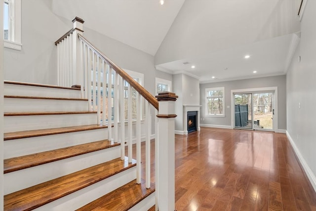 stairway with ornamental molding, vaulted ceiling, and hardwood / wood-style flooring