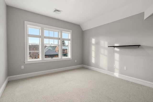 carpeted empty room featuring vaulted ceiling