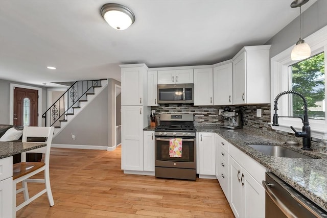 49 Pinehurst Ave, Methuen, MA 01844 - kitchen with appliances with stainless steel finishes, a sink, light wood-style floors, decorative backsplash, and white cabinetry