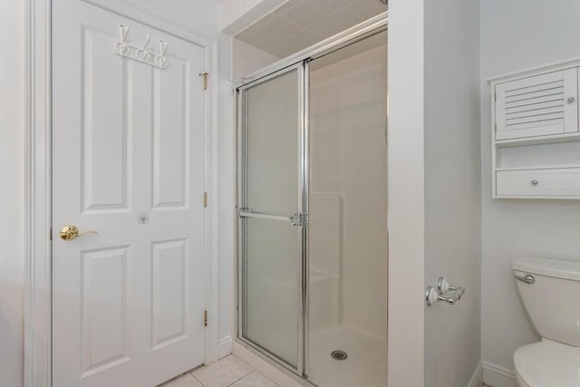 bathroom featuring tile patterned floors, toilet, and an enclosed shower