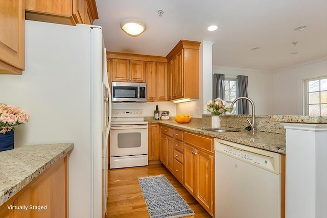 kitchen featuring sink, white appliances, light stone countertops, and a healthy amount of sunlight