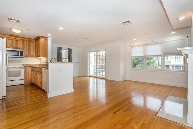 kitchen featuring kitchen peninsula, white appliances, light stone counters, and light hardwood / wood-style flooring