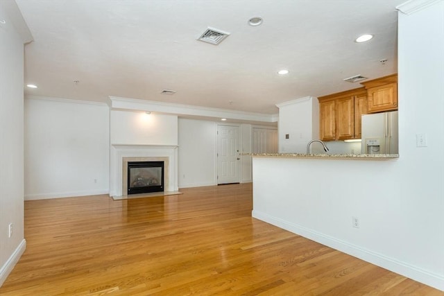 unfurnished living room with crown molding and light hardwood / wood-style flooring