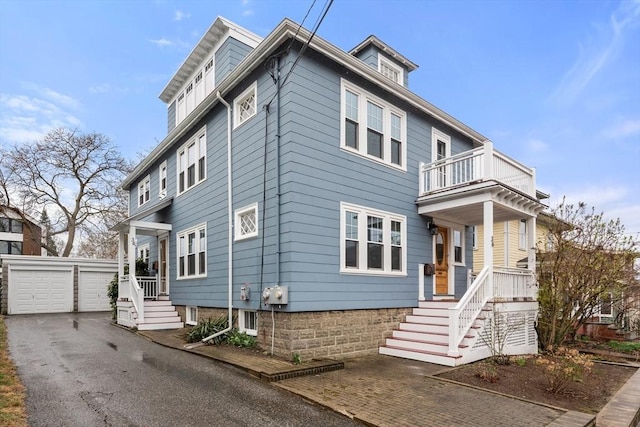 american foursquare style home with a detached garage, an outdoor structure, and a balcony