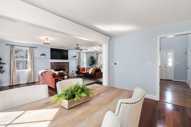 dining space featuring a wealth of natural light, baseboards, dark wood-style floors, and a fireplace