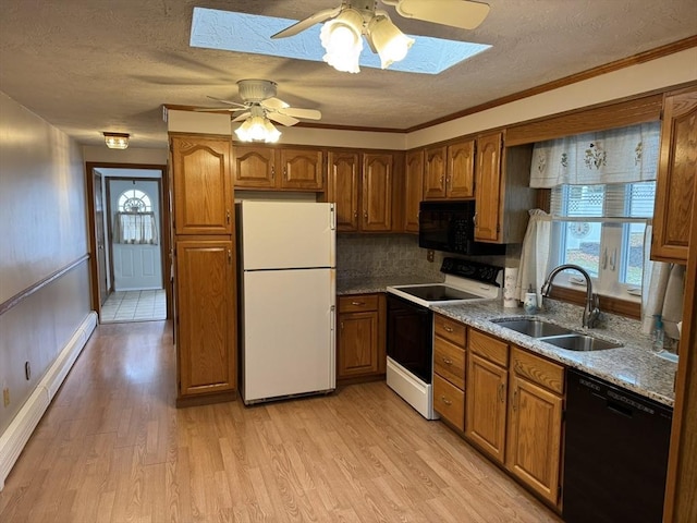 kitchen with black appliances, sink, a wealth of natural light, and a skylight