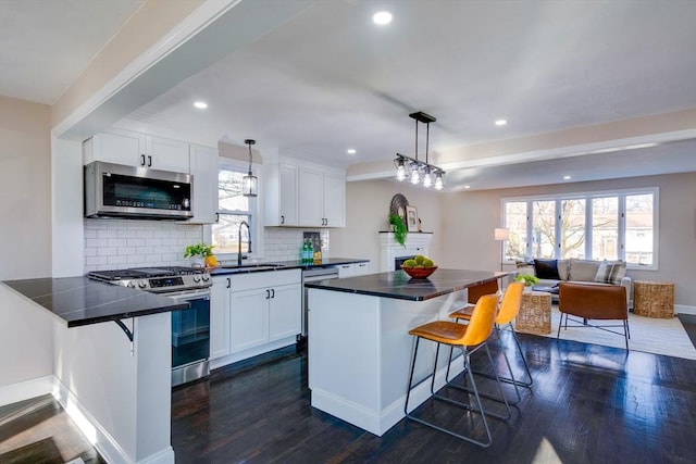 kitchen featuring a kitchen bar, white cabinetry, pendant lighting, and appliances with stainless steel finishes