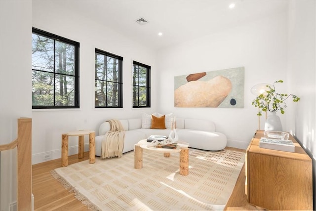 living area with light wood-style flooring, visible vents, baseboards, and recessed lighting