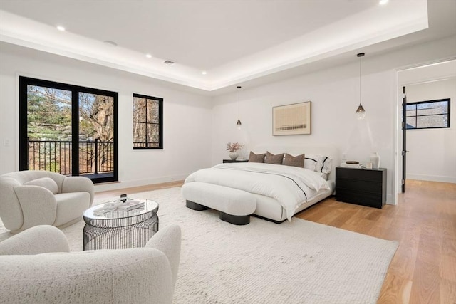 bedroom featuring recessed lighting, baseboards, access to outside, a tray ceiling, and light wood finished floors