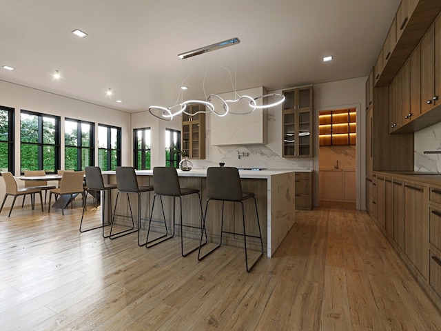 kitchen featuring a kitchen bar, sink, tasteful backsplash, and light wood-type flooring