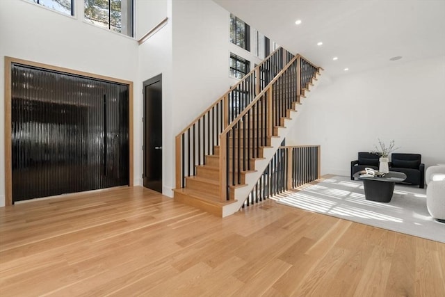 entryway with stairs, a high ceiling, wood finished floors, and recessed lighting