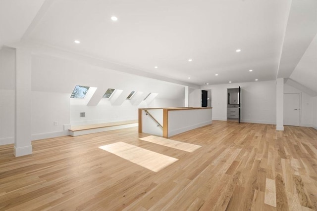 additional living space featuring baseboards, recessed lighting, a skylight, and light wood-style floors