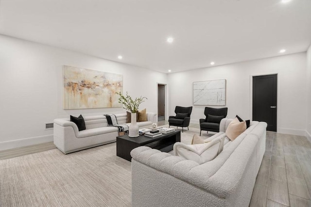 living room featuring light wood-type flooring, baseboards, and recessed lighting