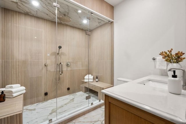 bathroom with marble finish floor, a shower stall, and vanity