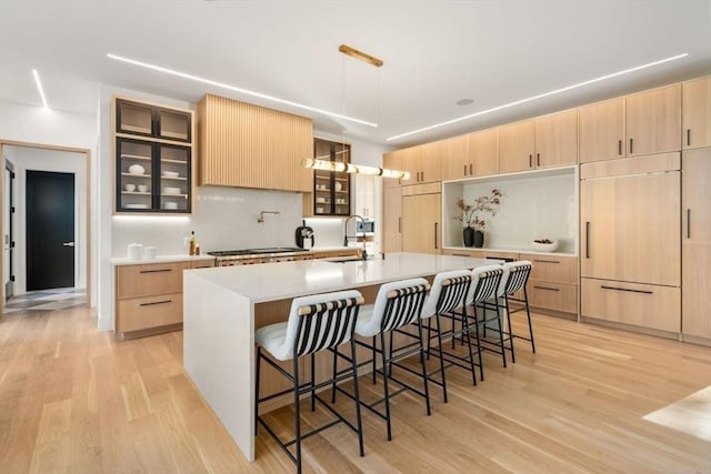 kitchen featuring light wood-style flooring, light brown cabinets, a kitchen breakfast bar, and a sink