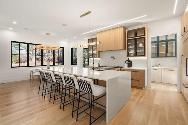 kitchen with light countertops, a large island, a breakfast bar area, and light wood-style flooring