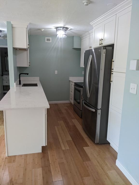 77 Adams St Unit 109, Quincy, MA 02169 - kitchen with appliances with stainless steel finishes, a sink, light wood finished floors, and baseboards